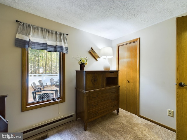 interior space featuring carpet, a textured ceiling, and a baseboard heating unit