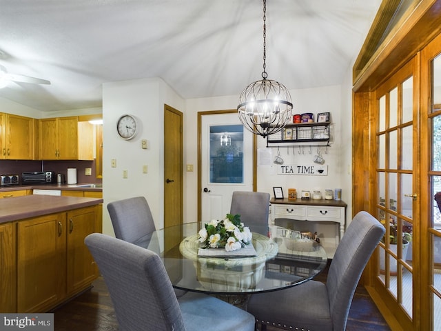 dining area featuring french doors, ceiling fan with notable chandelier, dark wood-type flooring, and lofted ceiling