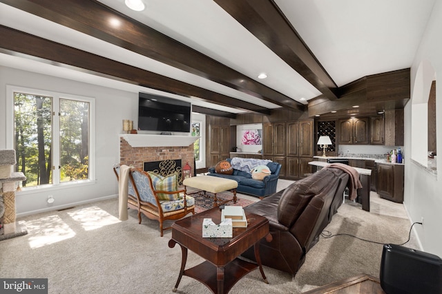 living room featuring light colored carpet, beamed ceiling, and a fireplace