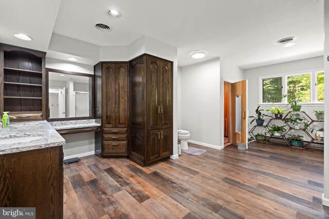 kitchen with dark brown cabinetry, sink, light stone countertops, and dark wood-type flooring