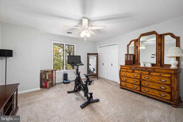 exercise area featuring light carpet and ceiling fan