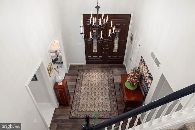 foyer with a notable chandelier, a towering ceiling, and dark wood-type flooring