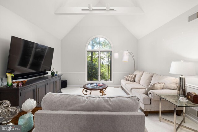 carpeted living room with vaulted ceiling with beams