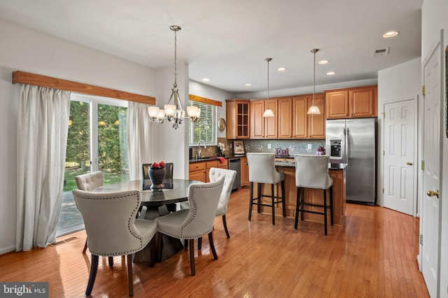 dining space featuring sink, a chandelier, and light hardwood / wood-style floors