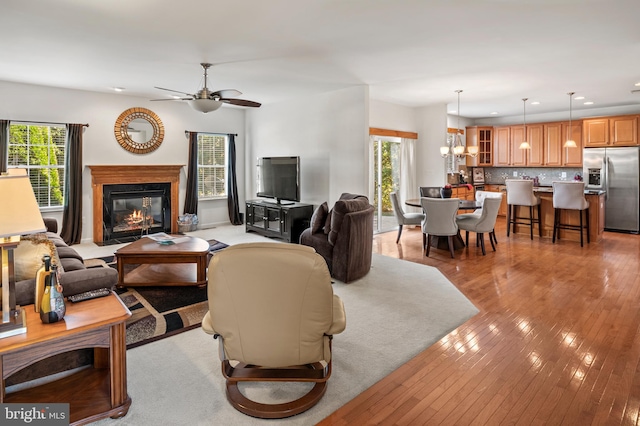 living room featuring ceiling fan with notable chandelier and light wood-type flooring