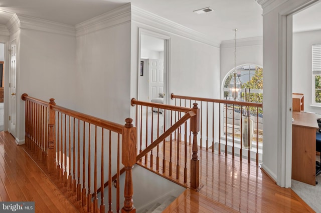 hallway featuring ornamental molding, light wood-type flooring, and an inviting chandelier