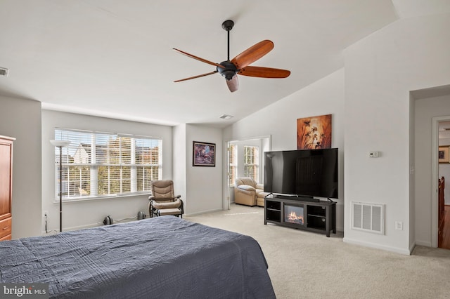 carpeted bedroom with ceiling fan, multiple windows, and vaulted ceiling