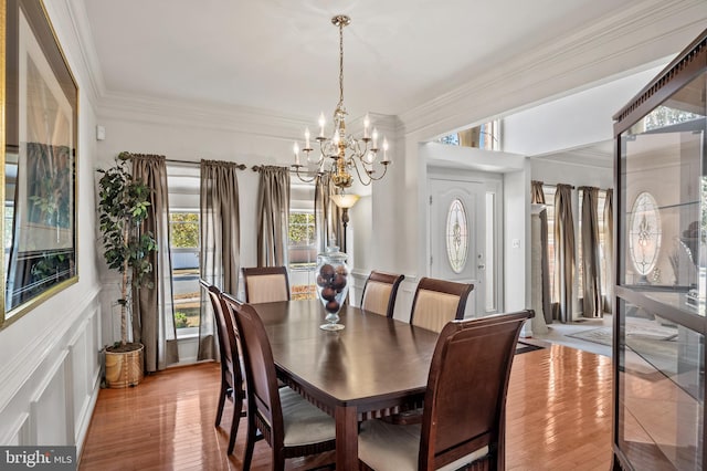 dining area with crown molding, light hardwood / wood-style flooring, and an inviting chandelier