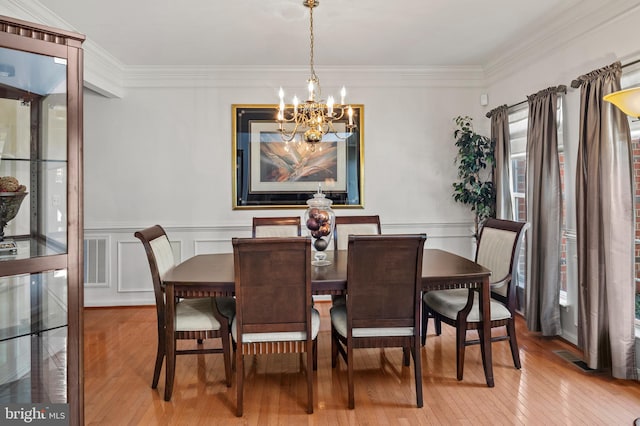 dining space with a notable chandelier, wood-type flooring, and ornamental molding