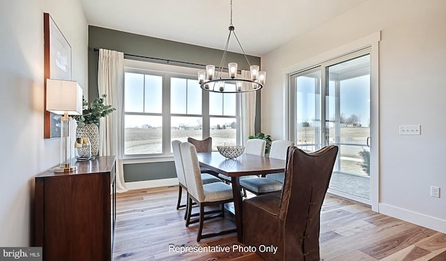 dining area with light hardwood / wood-style flooring, a wealth of natural light, and a notable chandelier