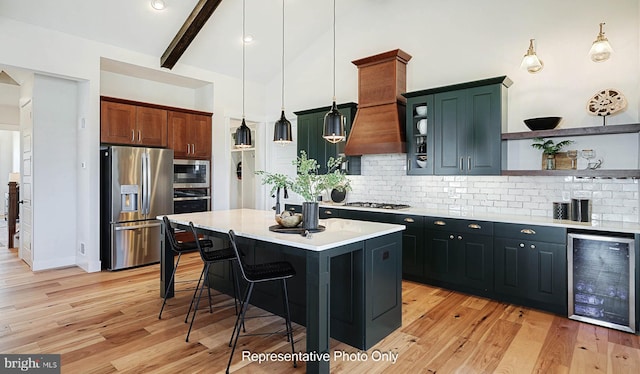 kitchen with pendant lighting, beverage cooler, stainless steel appliances, a center island, and light wood-type flooring