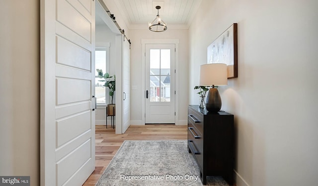 entrance foyer featuring light wood-type flooring, crown molding, a barn door, and wooden ceiling