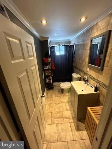 bathroom with tile walls, vanity, crown molding, toilet, and a shower with curtain