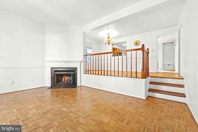 unfurnished living room featuring light parquet flooring, a textured ceiling, and a notable chandelier