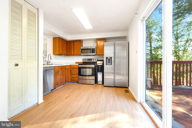 kitchen with stainless steel appliances, sink, and light hardwood / wood-style flooring