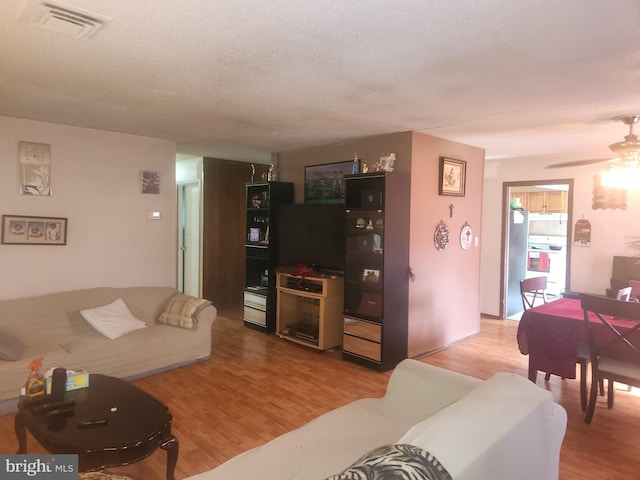 living room featuring a textured ceiling, ceiling fan, and light hardwood / wood-style flooring