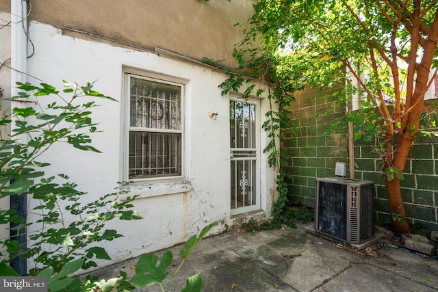 view of exterior entry with central AC unit and a patio area