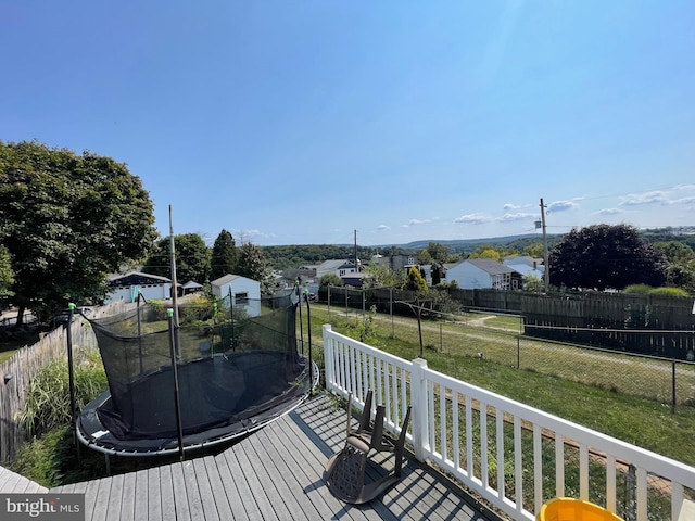 wooden terrace with a trampoline and a yard