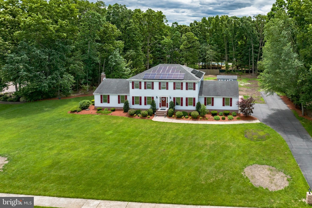 colonial house featuring solar panels and a front lawn