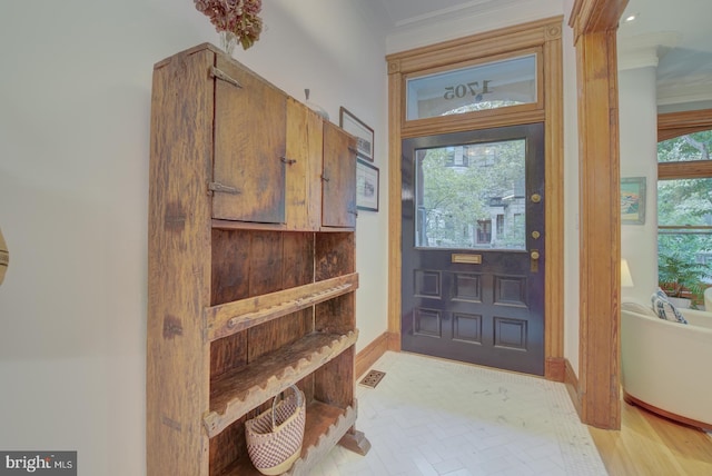 foyer with light wood-type flooring, a healthy amount of sunlight, and crown molding