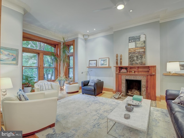 living room featuring ceiling fan, a fireplace, ornamental molding, and wood-type flooring