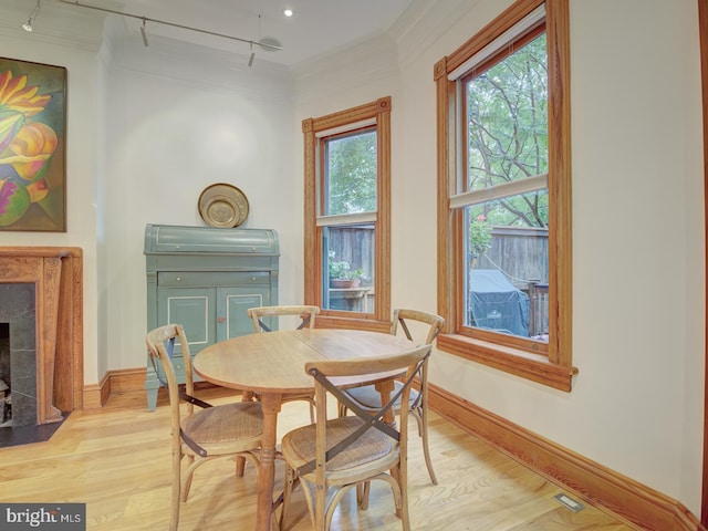 dining room featuring light hardwood / wood-style flooring, a high end fireplace, ornamental molding, and rail lighting