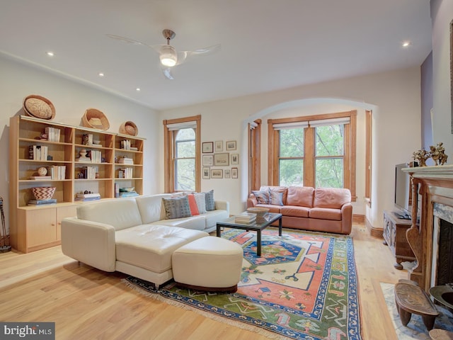 living room with ceiling fan, light hardwood / wood-style flooring, and a high end fireplace