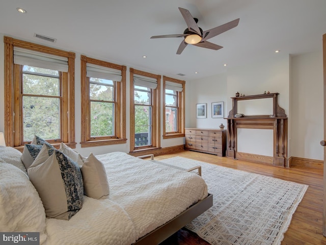 bedroom featuring ceiling fan, hardwood / wood-style flooring, and multiple windows