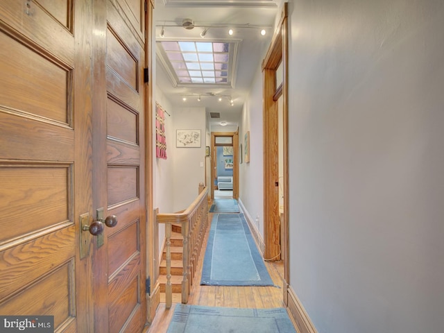 hall with light wood-type flooring and crown molding