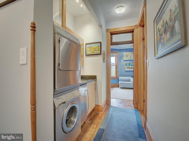 clothes washing area featuring light wood-type flooring and stacked washer and dryer