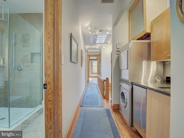 washroom featuring light wood-type flooring and stacked washing maching and dryer