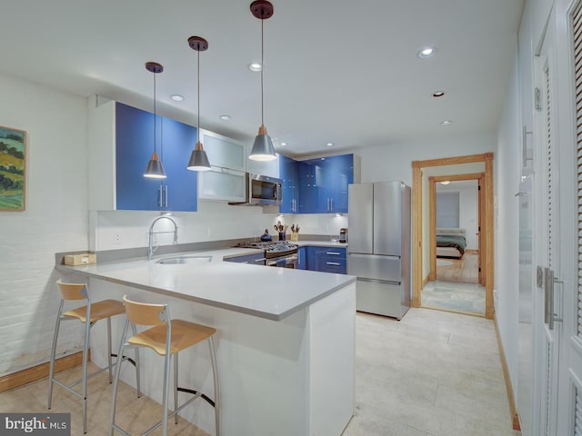 kitchen with kitchen peninsula, pendant lighting, blue cabinetry, stainless steel appliances, and sink