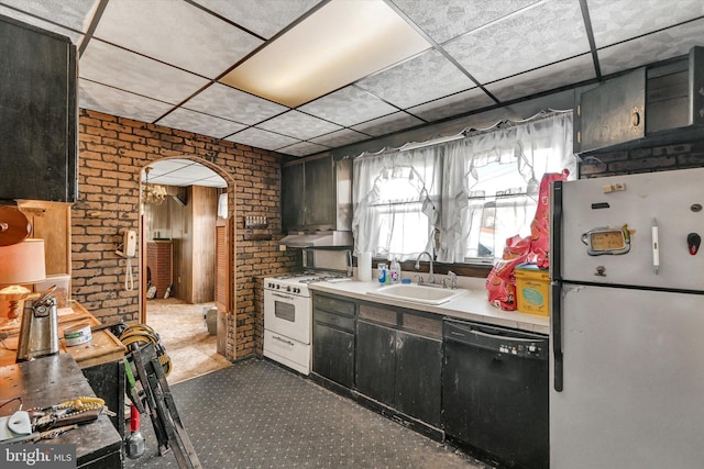 kitchen with sink, brick wall, white gas range oven, fridge, and dishwasher