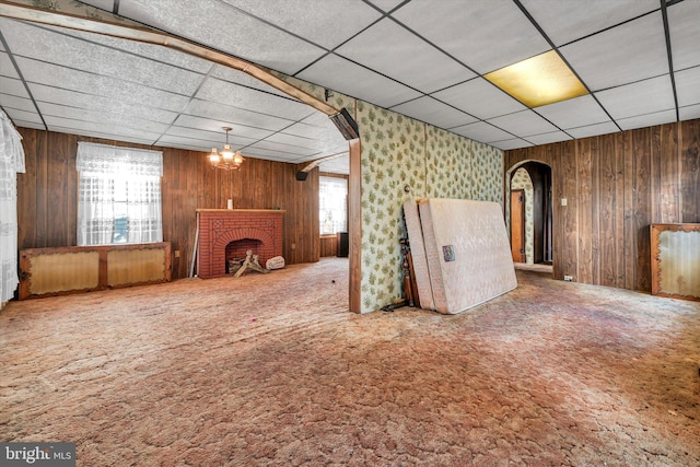 basement featuring a brick fireplace, a drop ceiling, carpet, and a healthy amount of sunlight