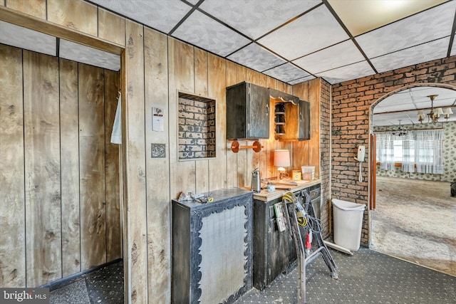 bar featuring carpet flooring, wood walls, and brick wall