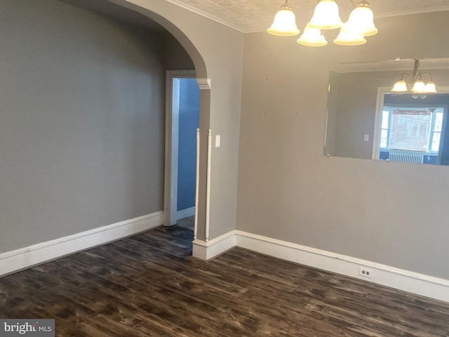 spare room featuring ornamental molding, a notable chandelier, and dark hardwood / wood-style flooring