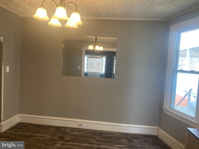 spare room featuring ornamental molding, dark wood-type flooring, and a notable chandelier