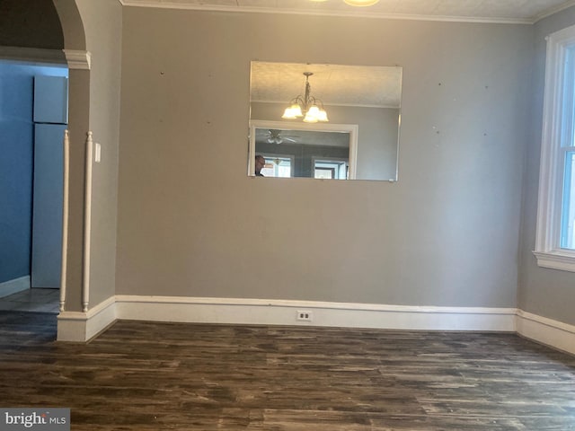 empty room featuring ornamental molding, dark hardwood / wood-style flooring, and a notable chandelier