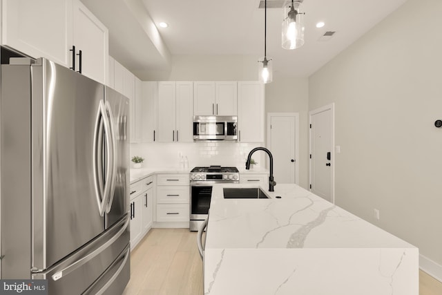 kitchen featuring white cabinets, appliances with stainless steel finishes, hanging light fixtures, and sink