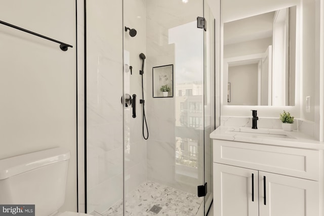 bathroom featuring vanity, a shower with shower door, and toilet