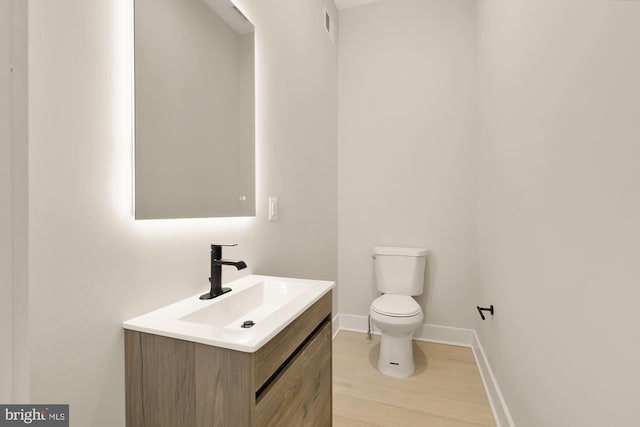 bathroom with hardwood / wood-style floors, vanity, and toilet