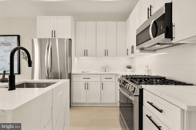 kitchen featuring stainless steel appliances, light stone countertops, and white cabinetry