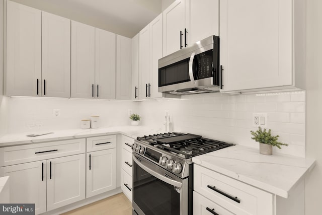 kitchen featuring tasteful backsplash, appliances with stainless steel finishes, light stone counters, and white cabinetry