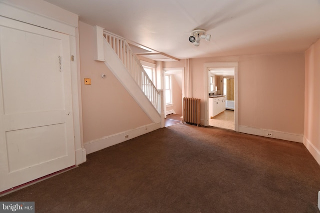 unfurnished room with radiator and dark colored carpet