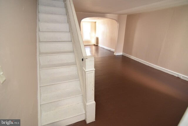 stairs with wood-type flooring and radiator heating unit