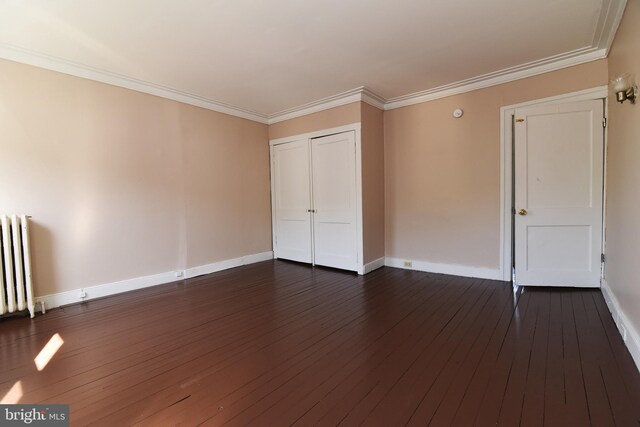 unfurnished bedroom with radiator, a closet, dark hardwood / wood-style floors, and crown molding