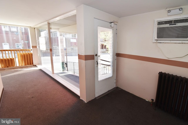 hallway with dark carpet, radiator heating unit, and a wall mounted AC