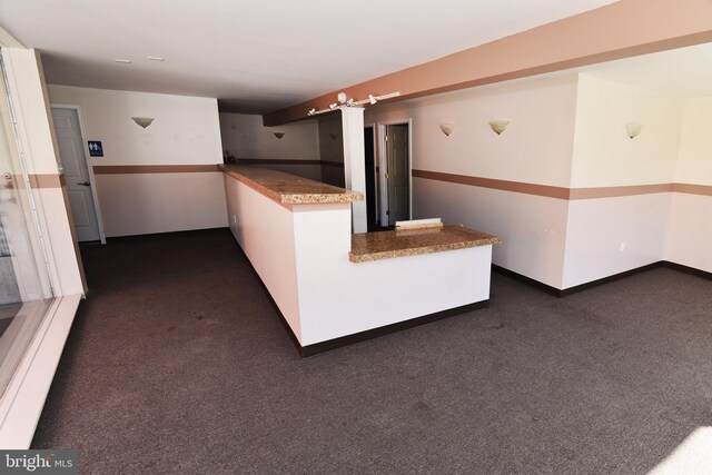 kitchen featuring dark carpet, kitchen peninsula, and white cabinetry