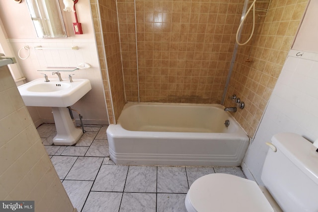 bathroom with tiled shower / bath combo, tile walls, and toilet