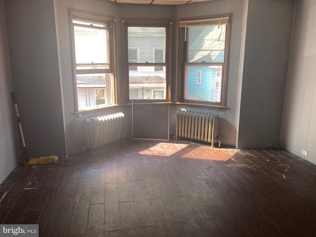 unfurnished room featuring radiator, dark hardwood / wood-style flooring, and a healthy amount of sunlight